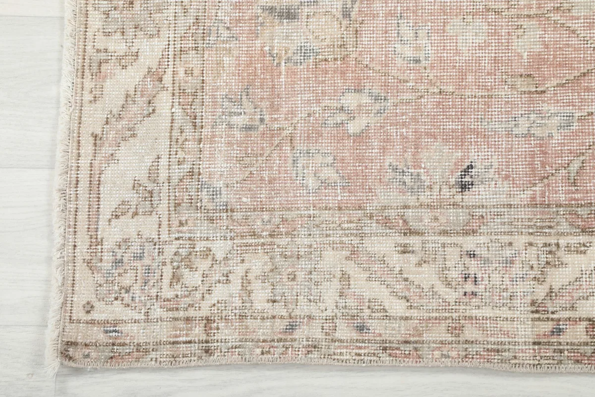 Detail of the rug's corner, showcasing the beige border pattern and slight wear