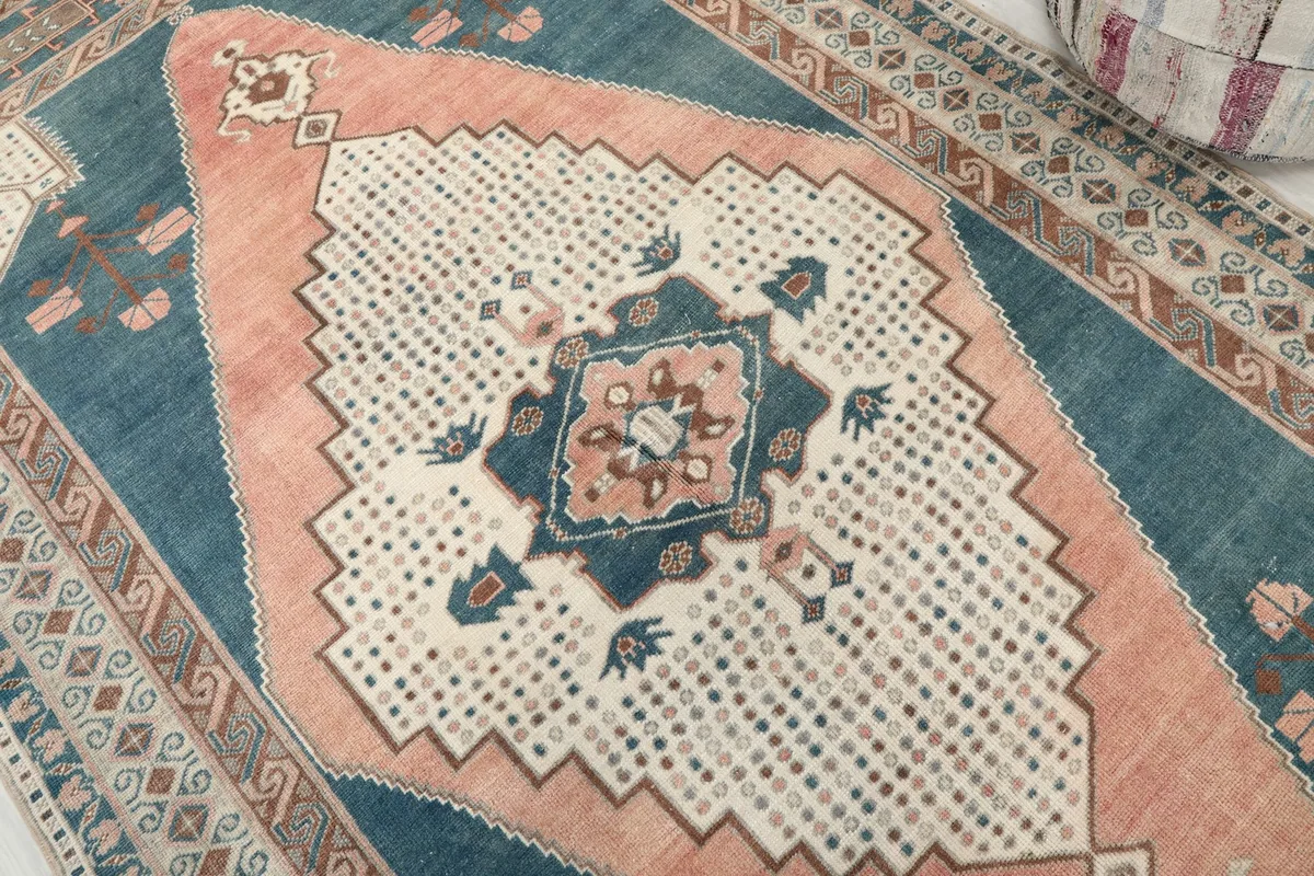 Detailed view of the central rose and ivory medallion with blue accents and geometric motifs