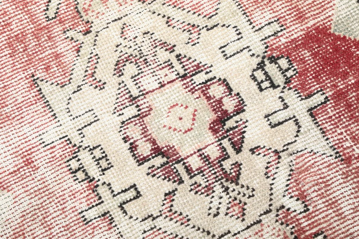 Detailed close-up of a central geometric medallion motif in cream, black, and rose