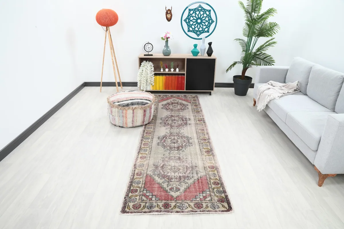 Vintage runner rug in a modern living room setting, showing its scale and color next to a sofa.