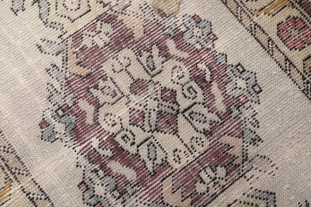 Detailed close-up of a central geometric medallion, revealing the hand-knotted wool pile and color variations.
