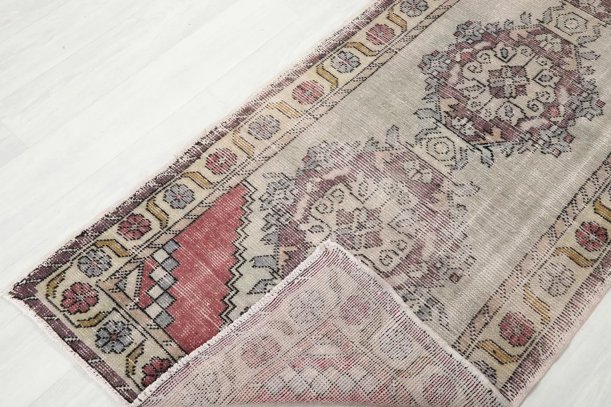 Corner of the rug folded back, showcasing the reverse side and the hand-knotted construction.