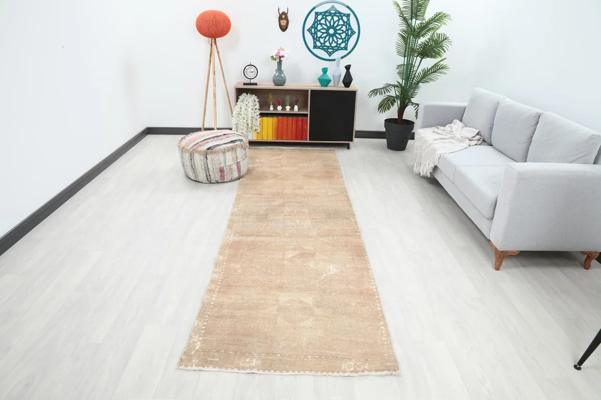 Vintage beige runner rug in a modern living room setting, extending from a cabinet towards a sofa.