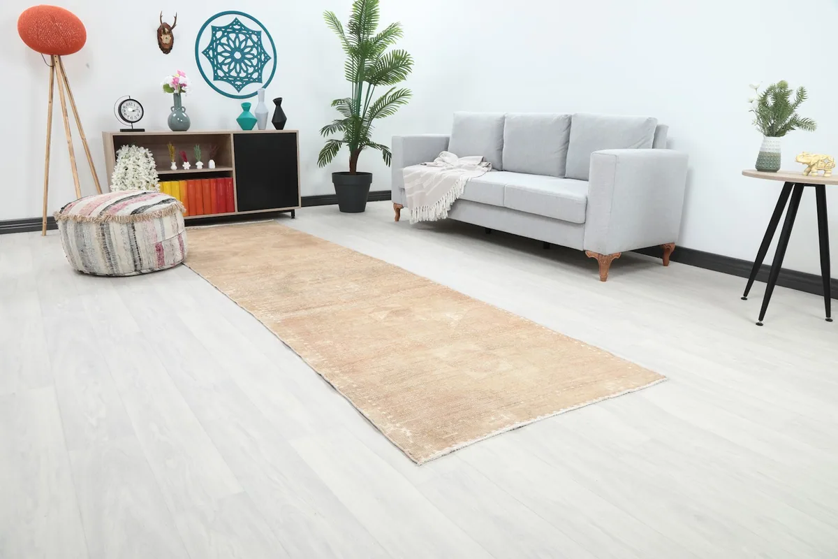 Angle view of the beige runner rug in a room, showcasing its length alongside a light gray sofa and decor.