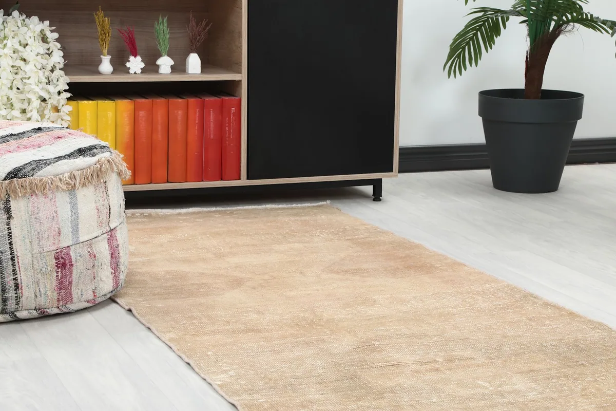 Close-up of the runner rug's end, showing its texture and subtle pattern near a colorful bookshelf and pouf.