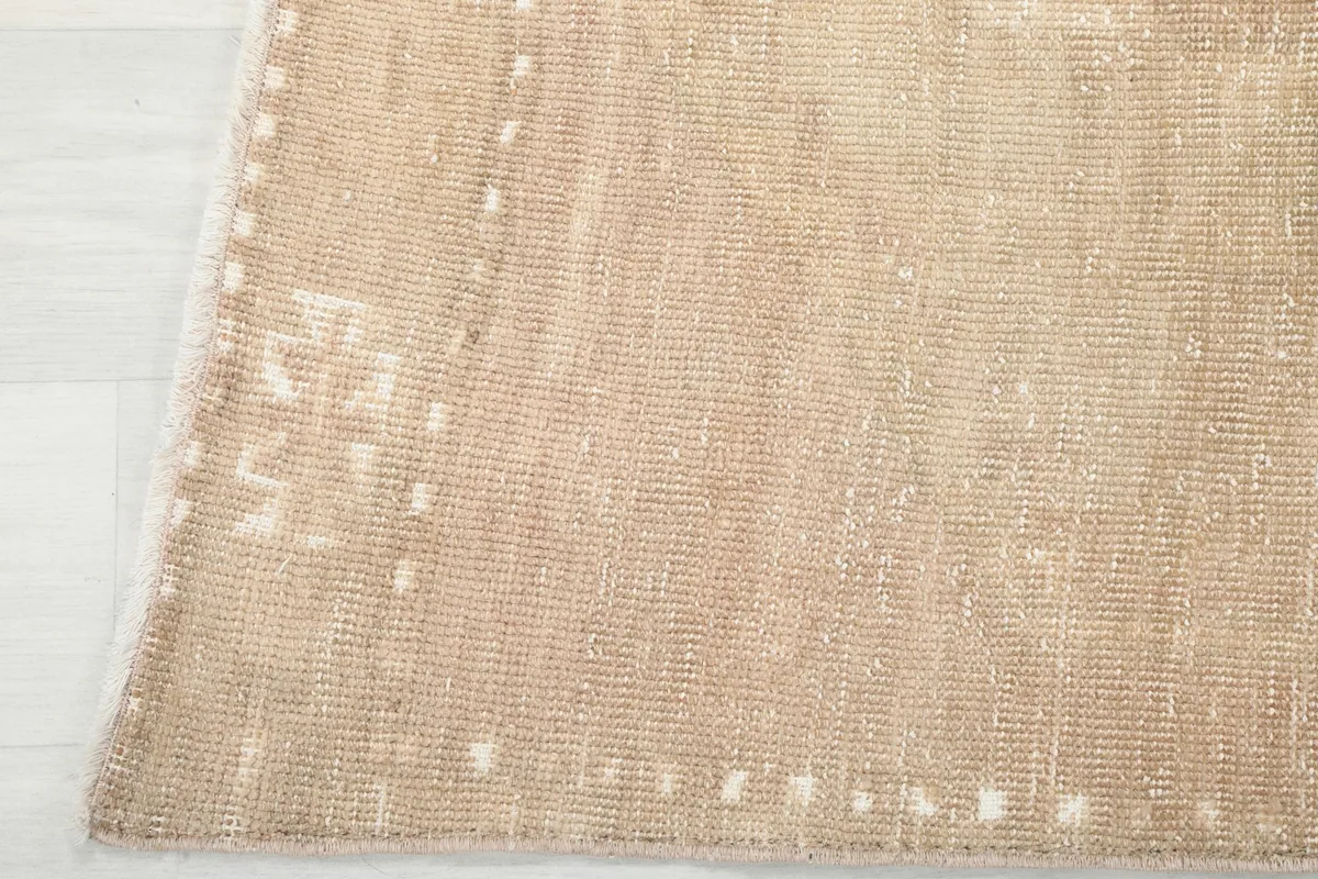 Detail of the rug's edge, showing the subtle border design and the texture of the hand-knotted wool.