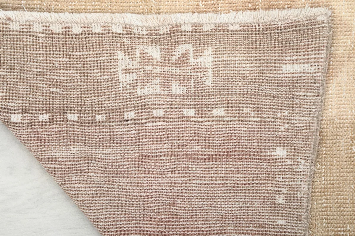 Close-up of the rug's back, detailing the tight weave of the cotton foundation and the knotting.