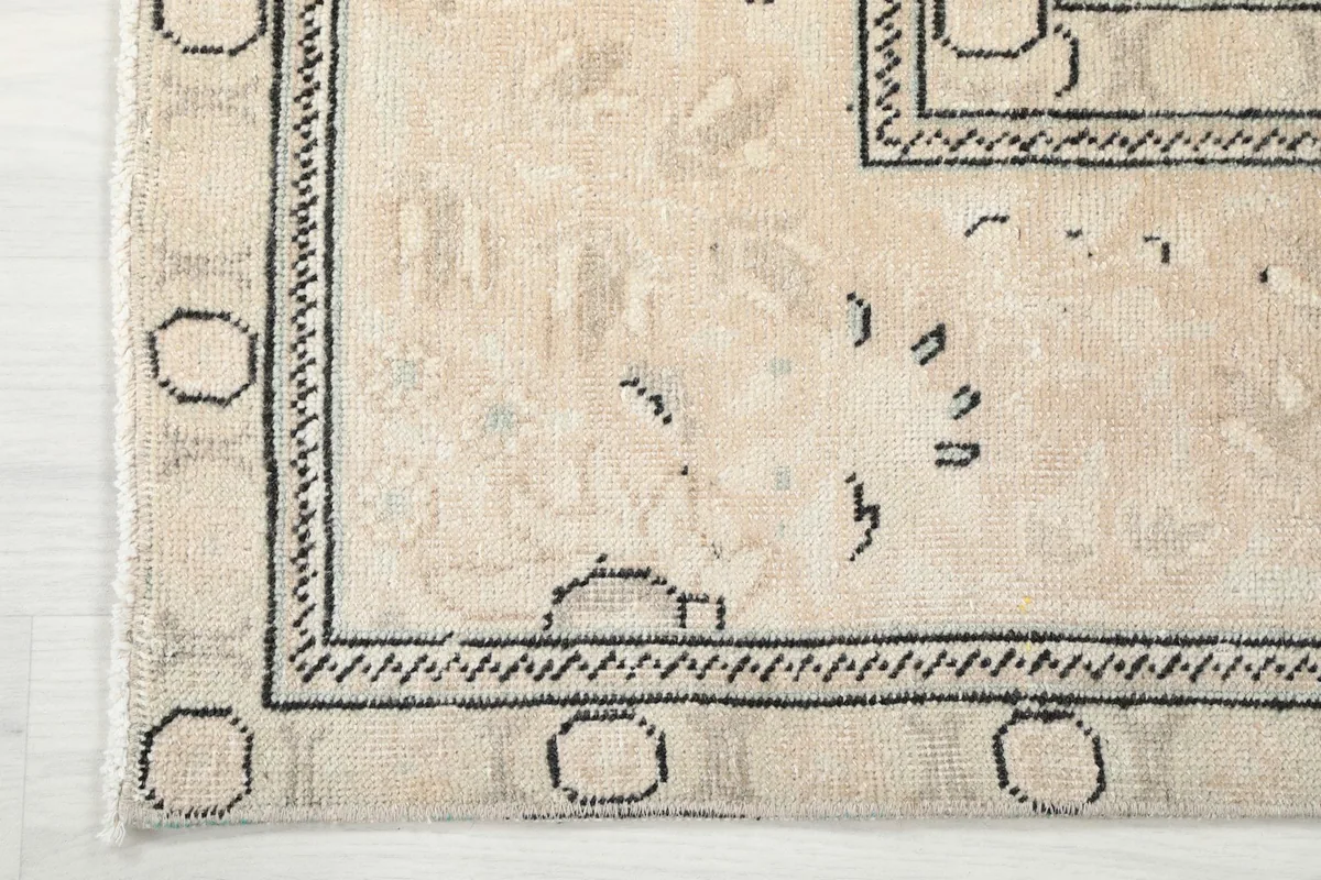 Corner detail of the rug's border, showcasing the hand-knotted structure and design
