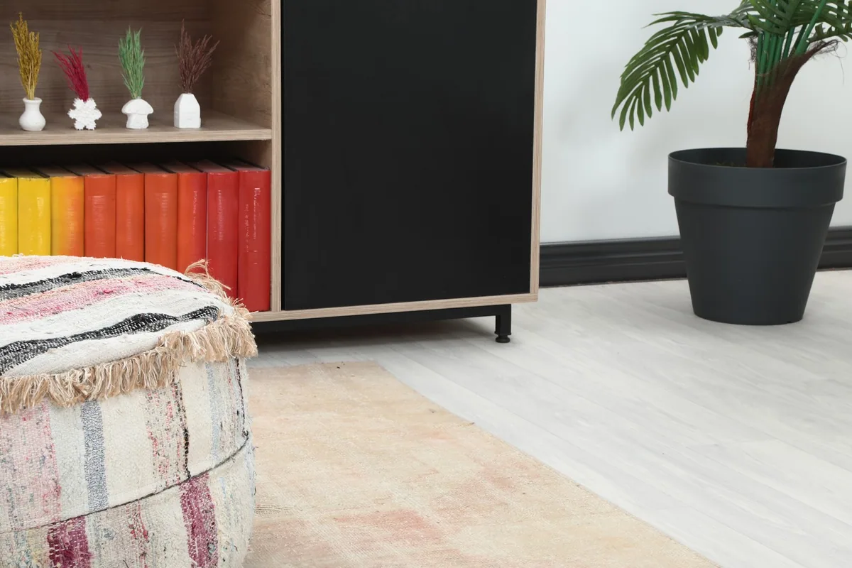 Close-up of the runner rug's end in a room, next to a decorative pouf and cabinet