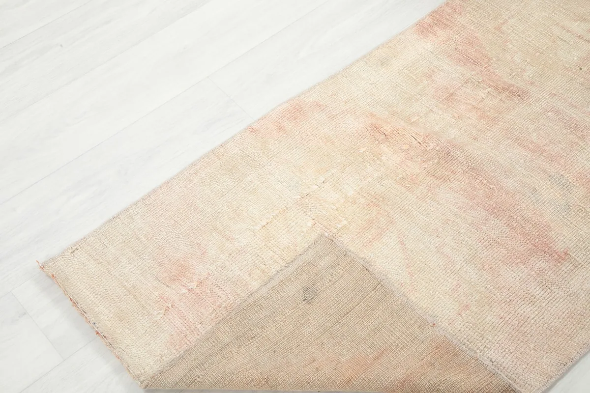 Corner of the rug lifted to show the back of the hand-knotted wool pile on cotton foundation