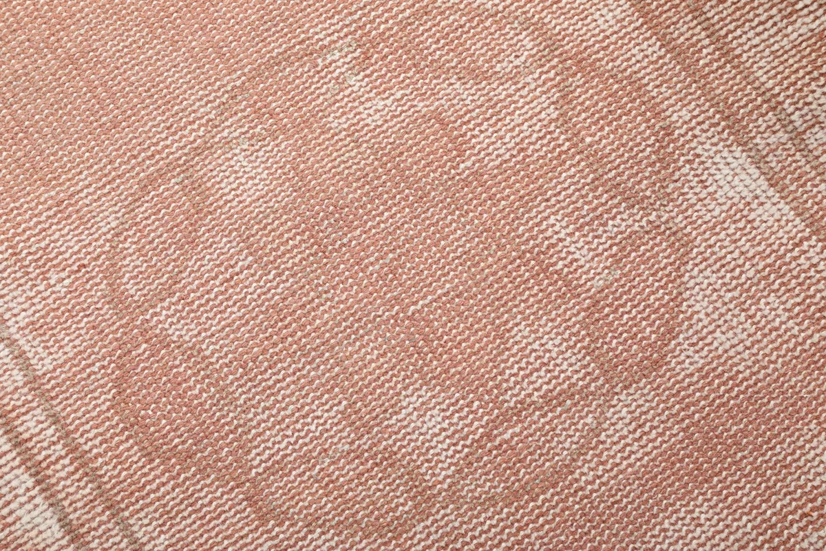 Close-up texture detail of the rose wool pile and visible cotton foundation
