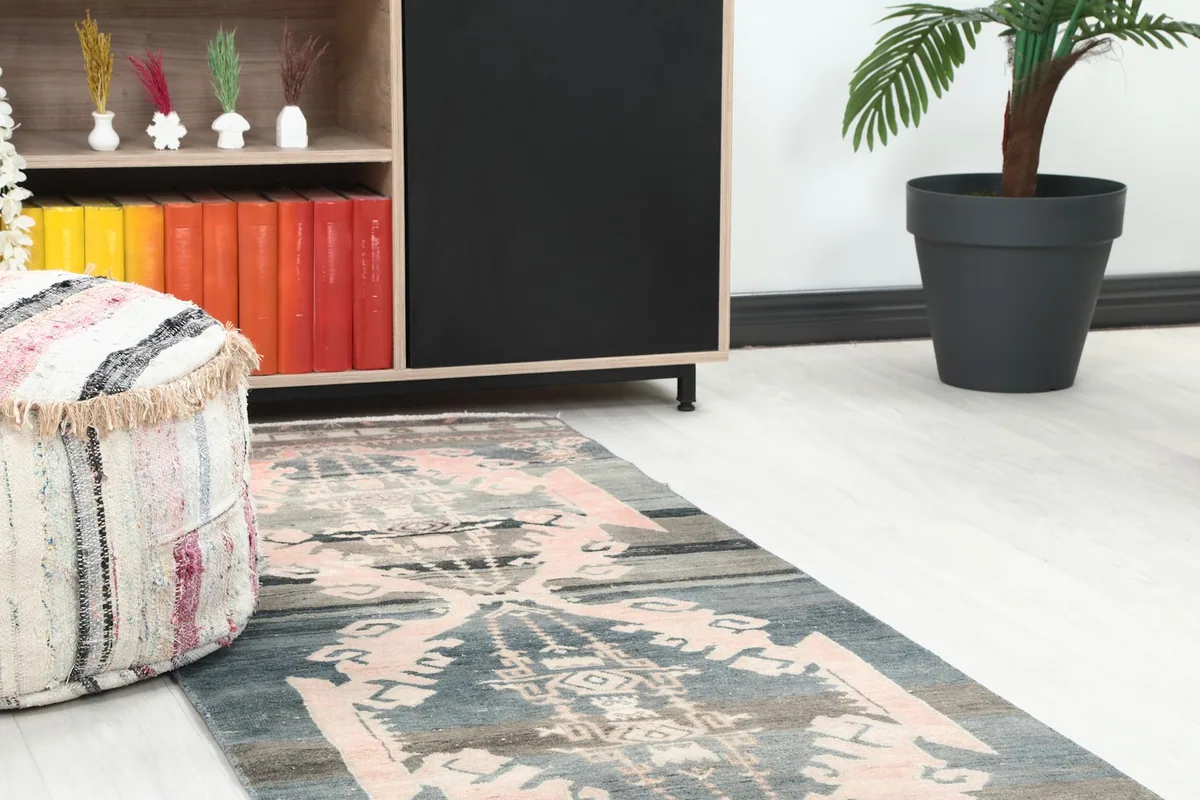 Close-up of the runner rug's pattern and colors, with a pouf and cabinet in the background.