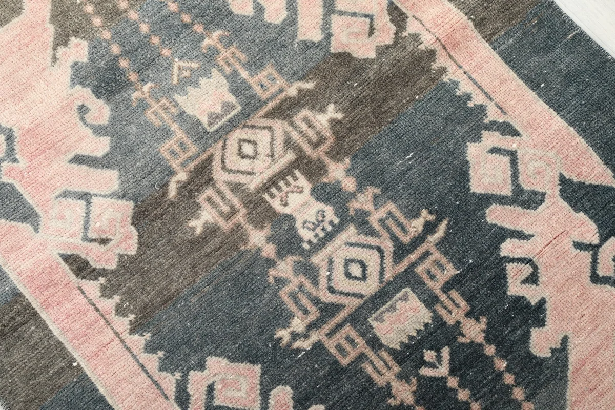 Detailed close-up of the central tribal motif and color variations in the rug's wool pile.