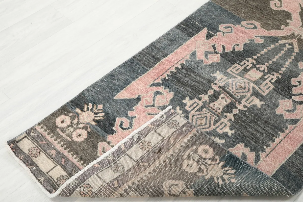 Corner of the runner rug folded back to reveal the back, showing the hand-knotted construction.