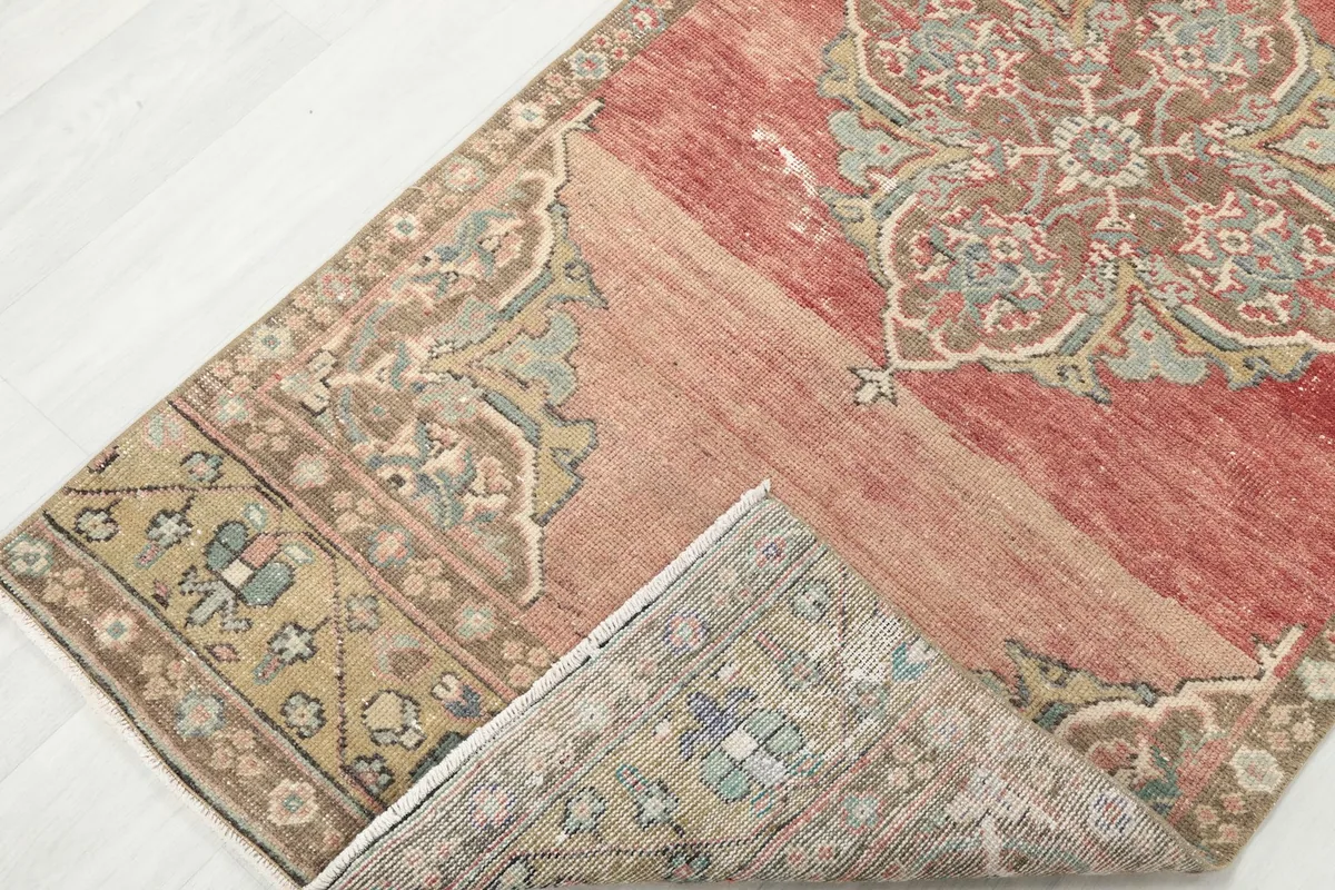 Corner of the rust runner rug folded to show the back and foundation
