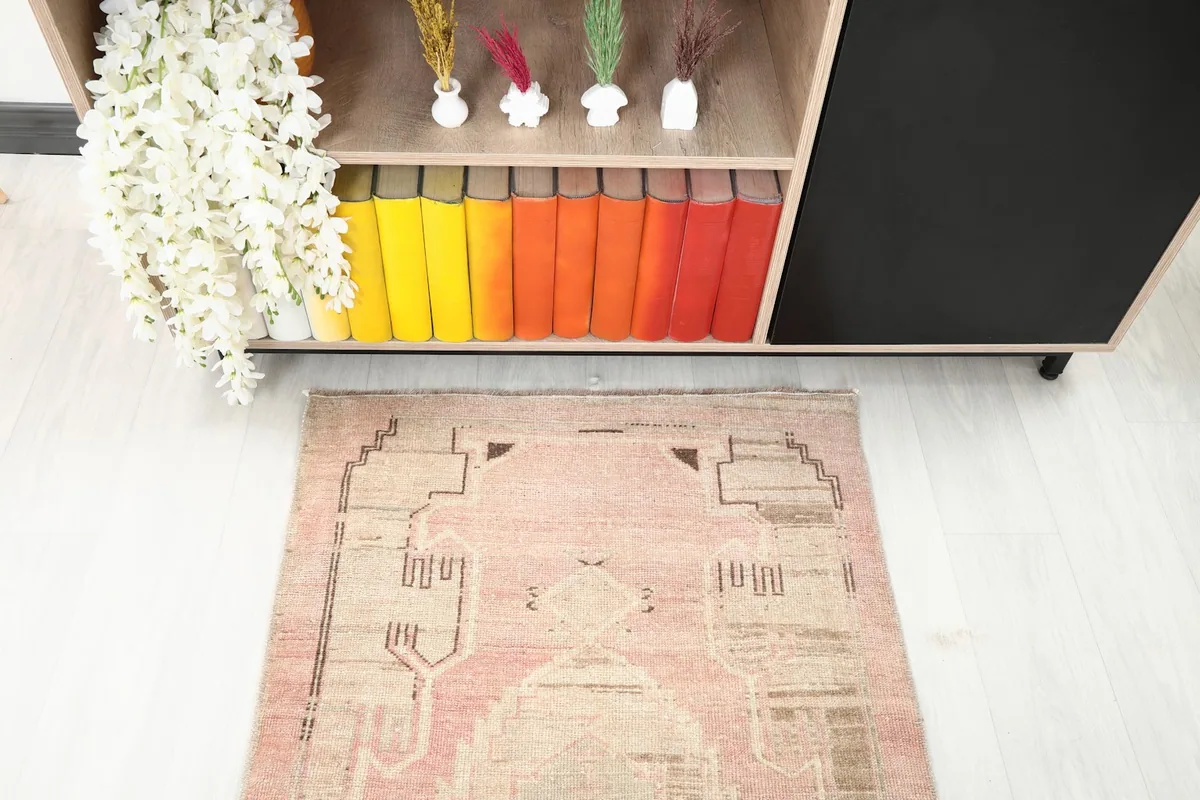 Detailed view of the geometric patterns and colors at one end of the rose and gray runner rug.