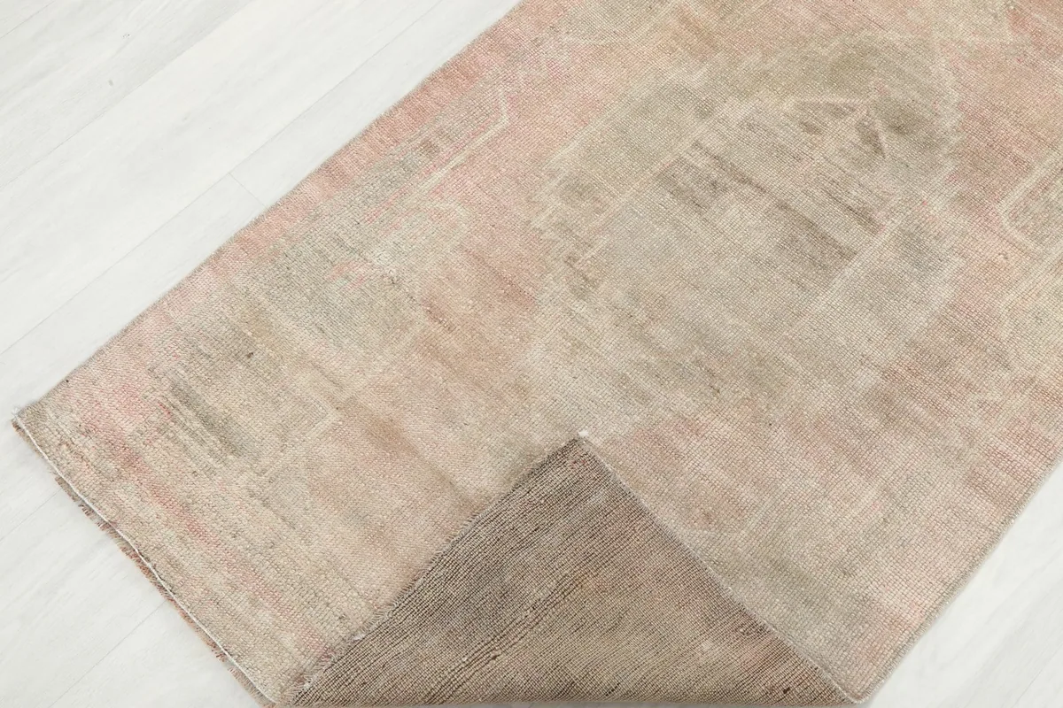 Corner of the runner rug folded back, revealing the cotton foundation and the reverse side.