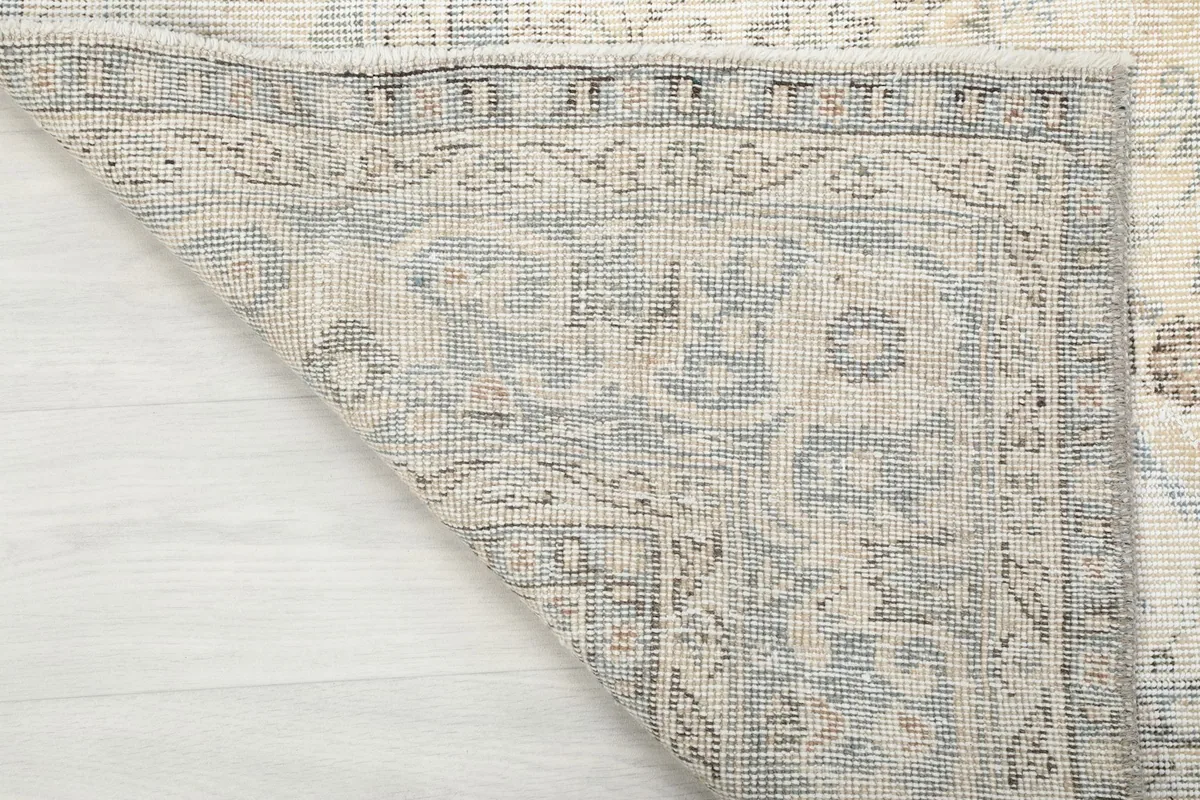 Underside corner of the rug, showing the hand-knotted cotton foundation and tight weave.