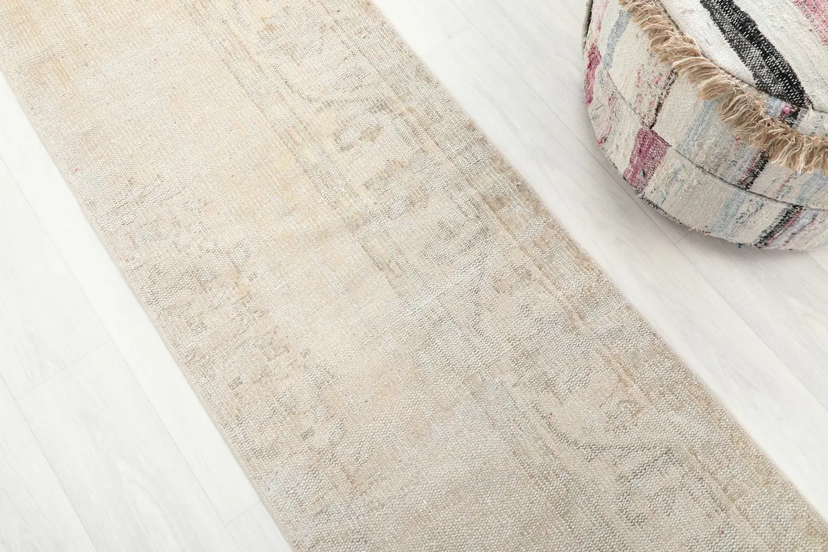 Detailed view of the distressed cream and beige wool pile, showing subtle geometric patterns