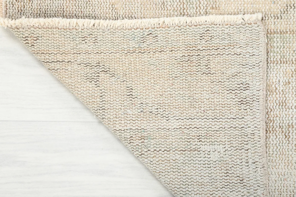 Edge of the rug with its natural fringe and the woven cotton foundation