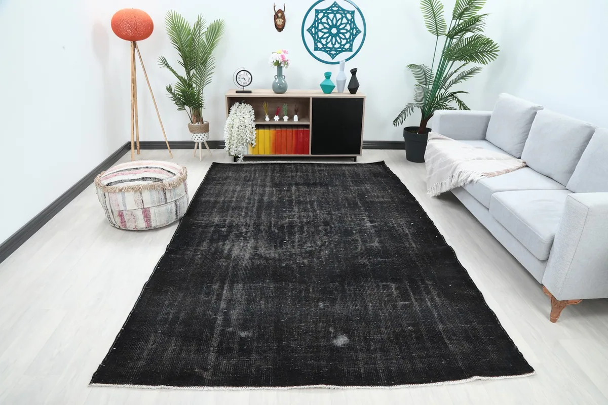 Charcoal vintage rug displayed in a bright living room setup with a gray sofa and decor, showing its full size.
