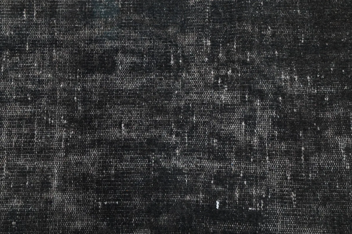 Close-up of the low pile of the charcoal rug, showing the hand-knotted wool fibers and natural wear.