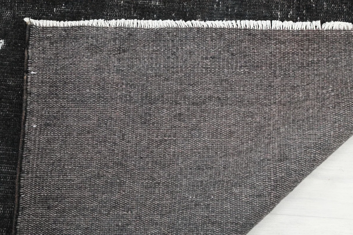 Close-up of the back of the rug, detailing the tight weave of the cotton foundation and finished edges.