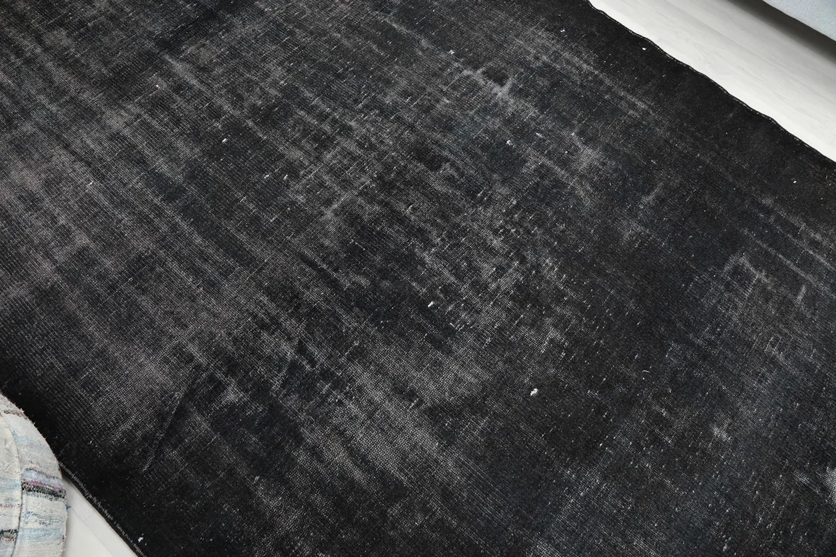 Overhead shot capturing the full distressed pattern and texture of the black and gray vintage rug.
