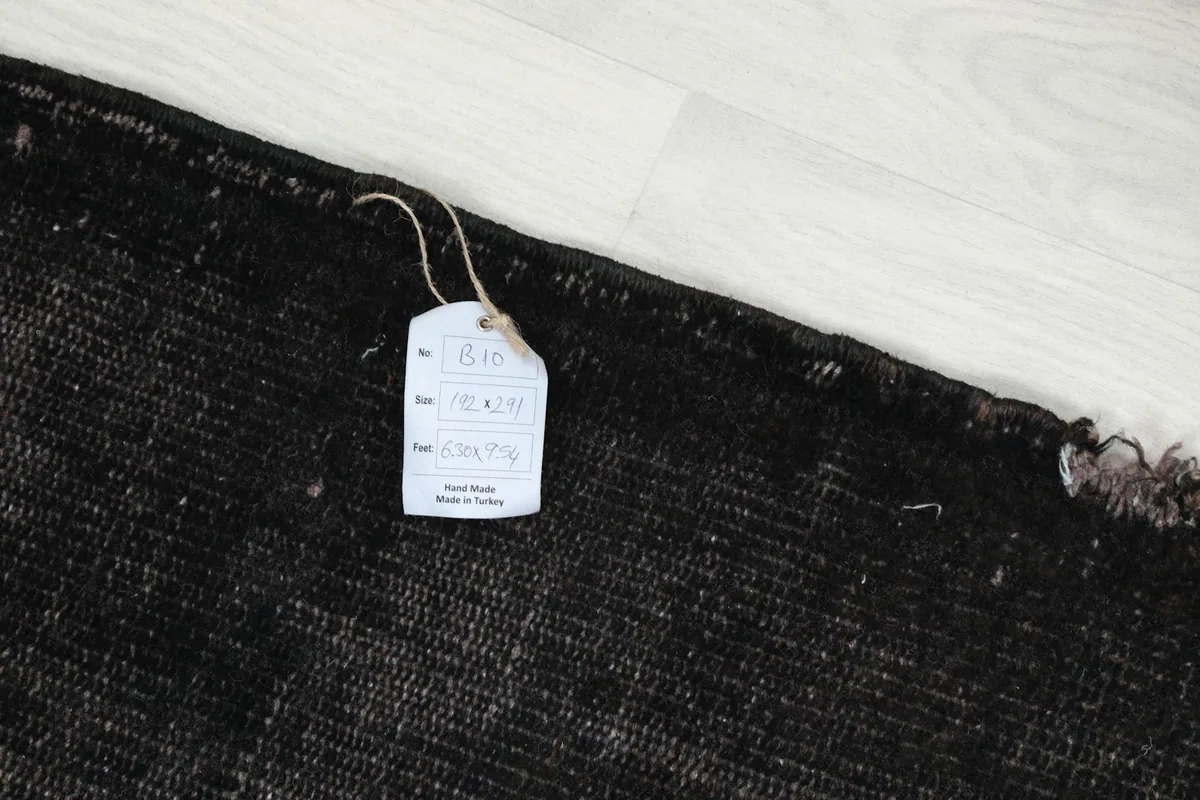 Close-up of a RugsKilim tag attached to the rug, showing details like size and origin.
