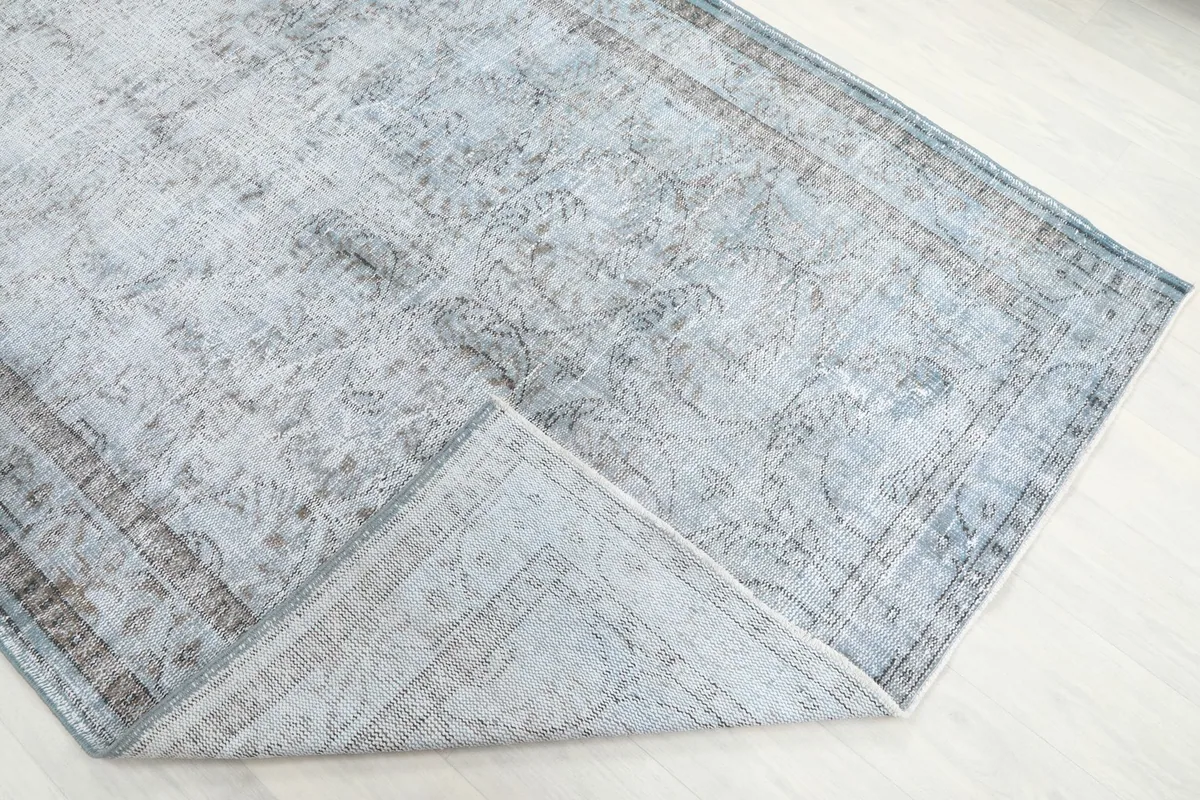 Corner of the rug folded back, revealing the hand-knotted wool pile