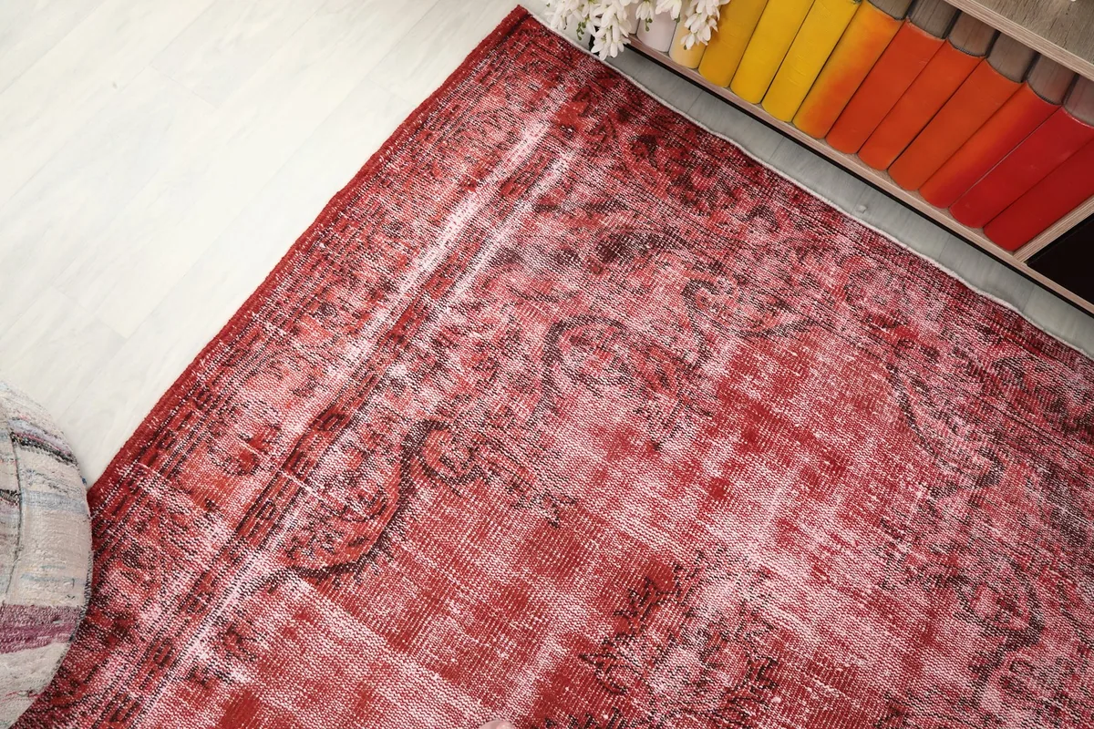 Corner view of the rug, detailing the distressed red color and pattern