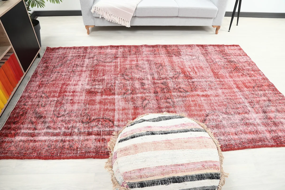 Overhead room view of the rug from a different angle, with a striped pouf