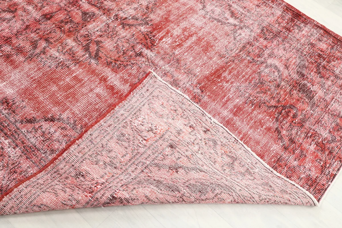 Corner of the rug folded back to reveal the cotton foundation and knotting