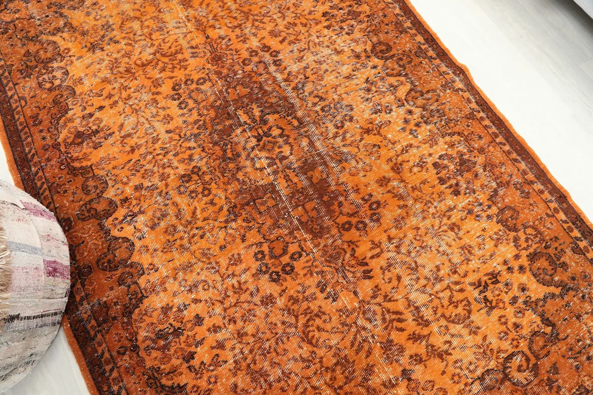Overhead angle of the vintage orange rug, emphasizing its overall distressed appearance.