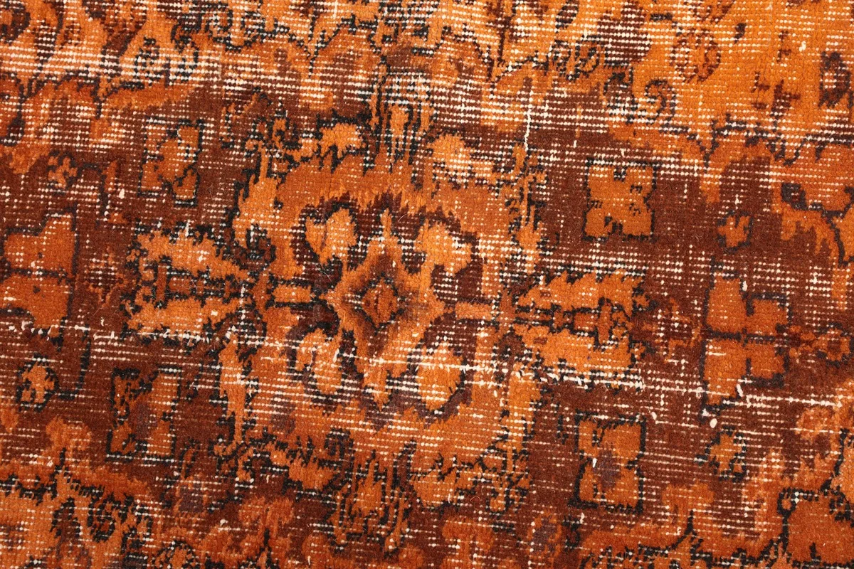 Close-up of the low wool pile and faded brown patterns on the orange field.