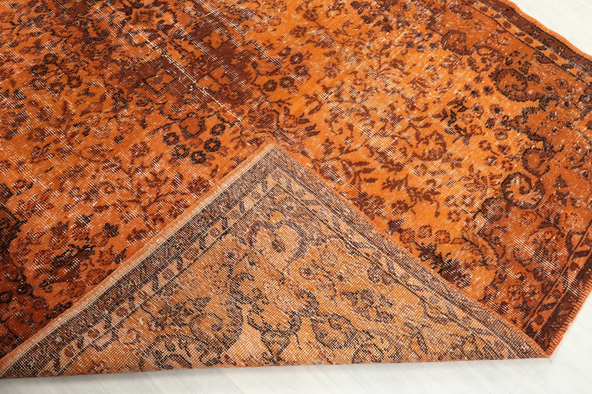 Corner of the rug folded back to reveal the hand-knotted cotton foundation and reverse side.