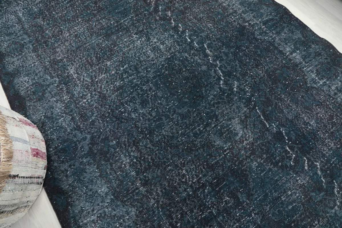 Overhead angle of the rug's central area, emphasizing the distressed wool and faint geometric motifs.