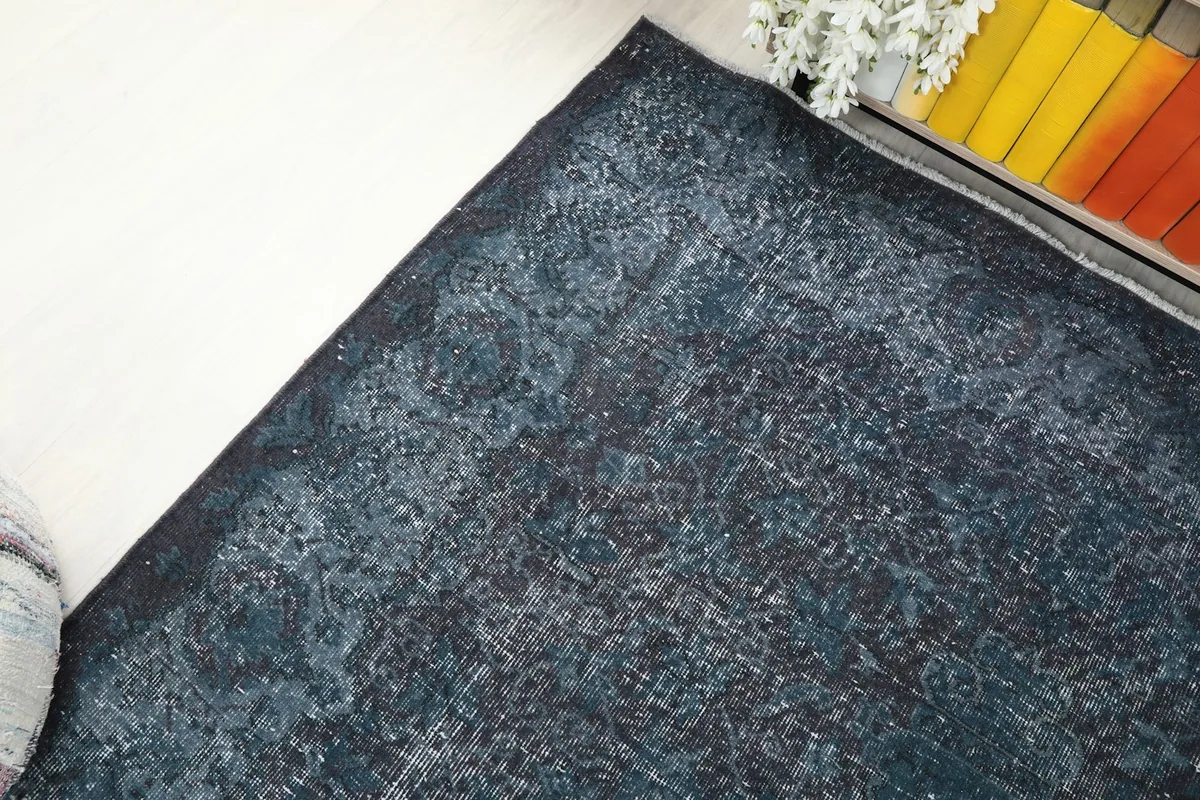 Top-down view of a rug corner, focusing on the distressed border design and color fading.