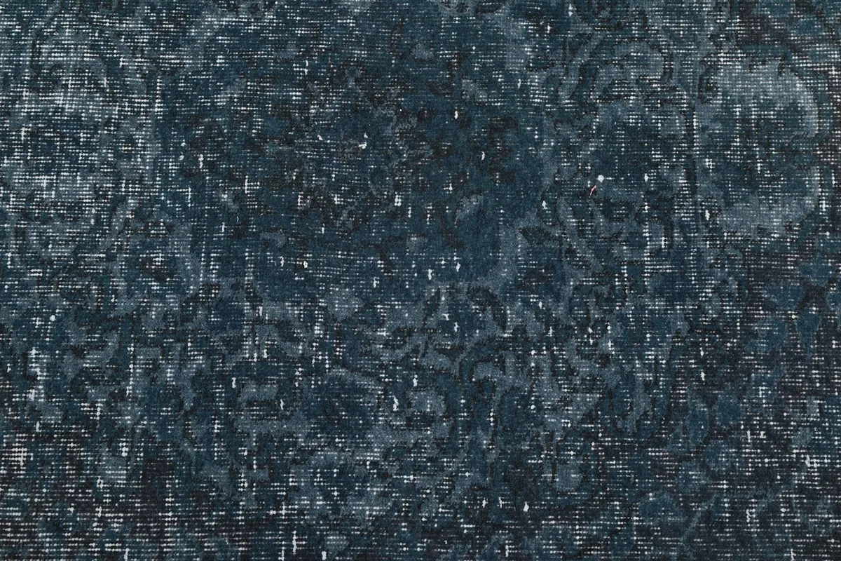 Close-up of the rug's low wool pile, revealing the hand-knotted texture and the blend of navy and lighter tones.