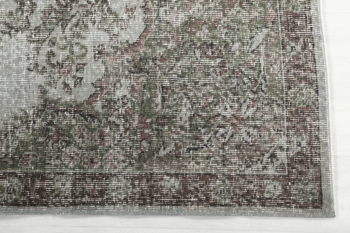 Detailed view of the rug's border and corner, highlighting the charcoal and muted green tones