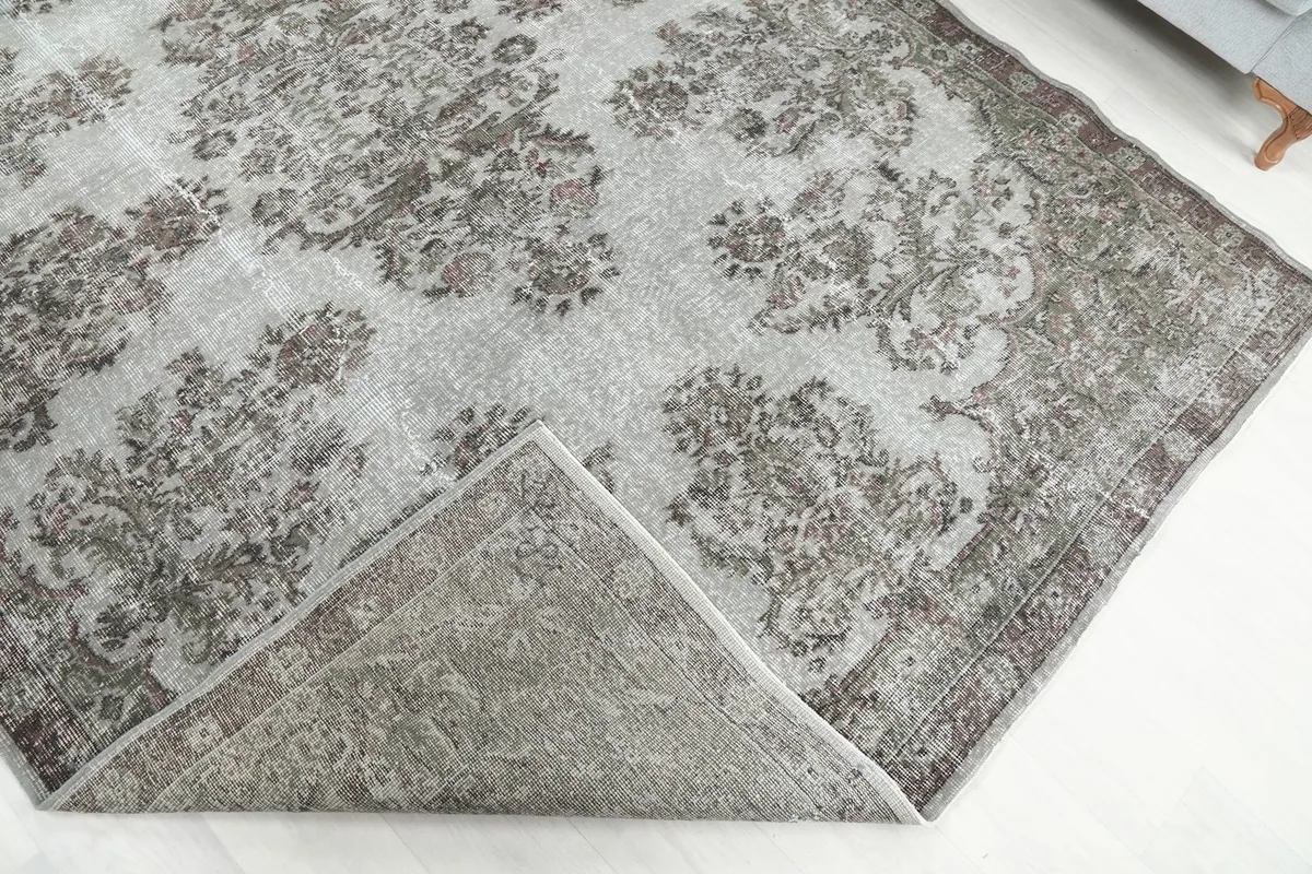 Corner of the rug folded back, showing the cotton foundation and reverse side of the hand-knotted construction