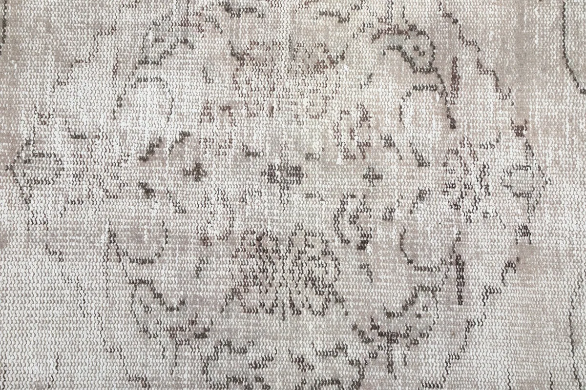 Close-up of the distressed wool pile, highlighting the texture and faded colors