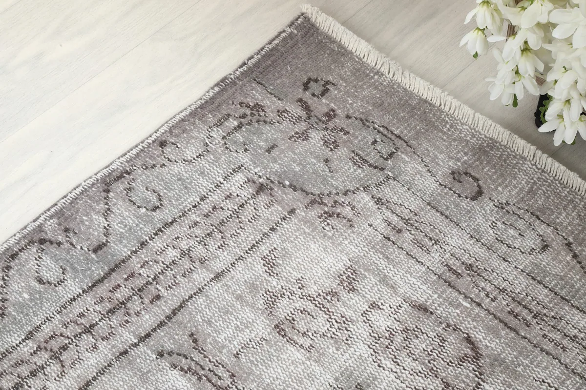 Corner detail of the gray vintage rug, showcasing the hand-knotted craftsmanship