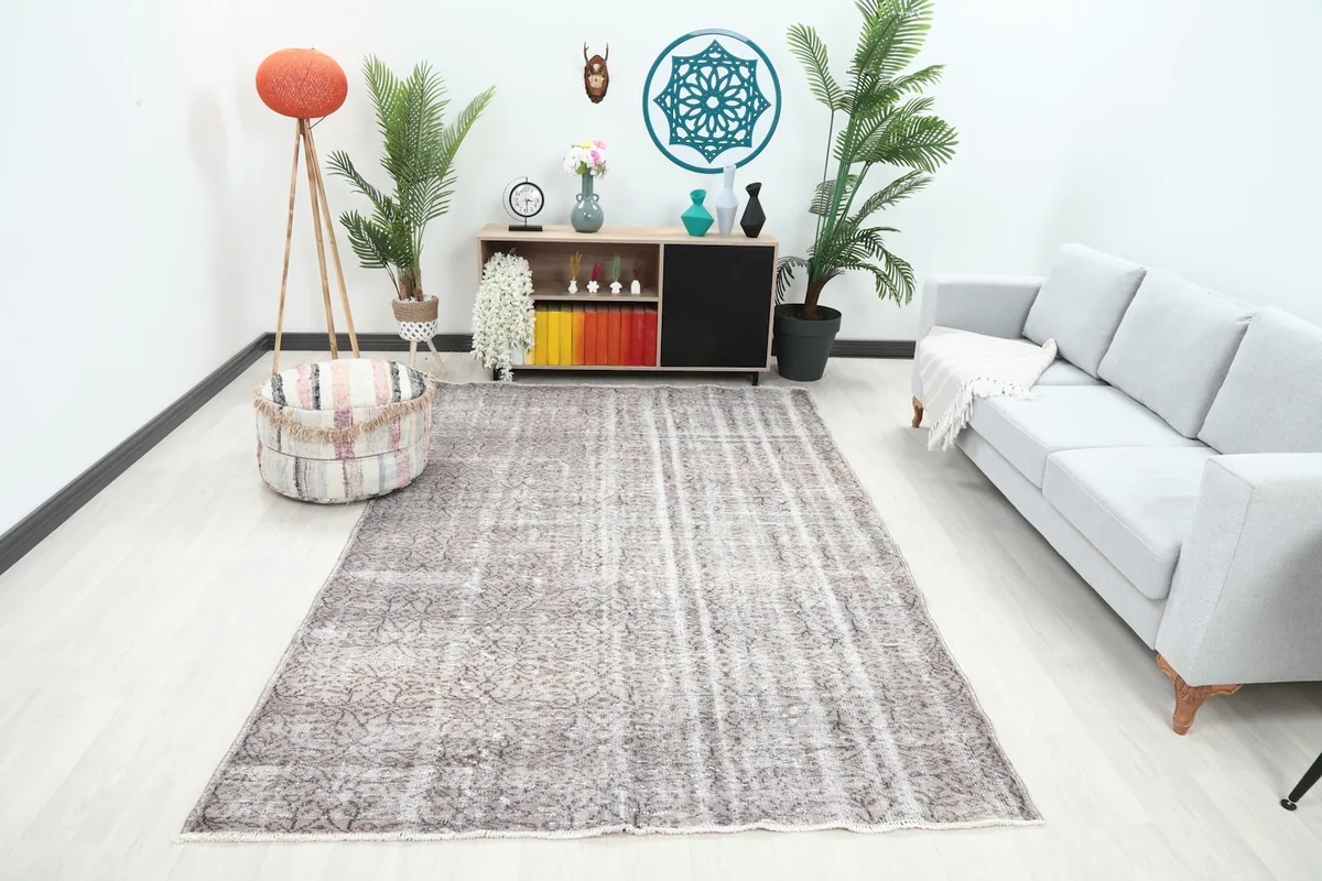 Vintage gray and beige area rug in a modern living room setting with a light gray sofa and wooden cabinet.