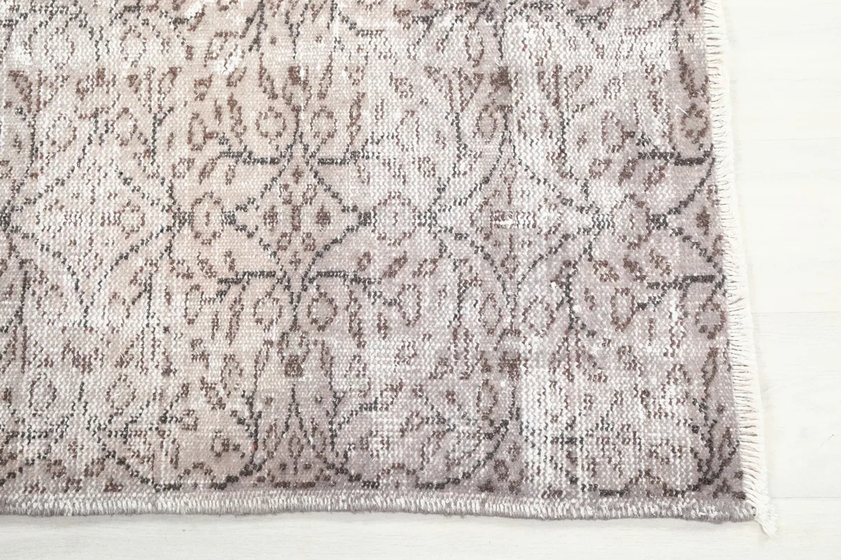 Detailed view of the faded floral and geometric patterns on the vintage wool rug.