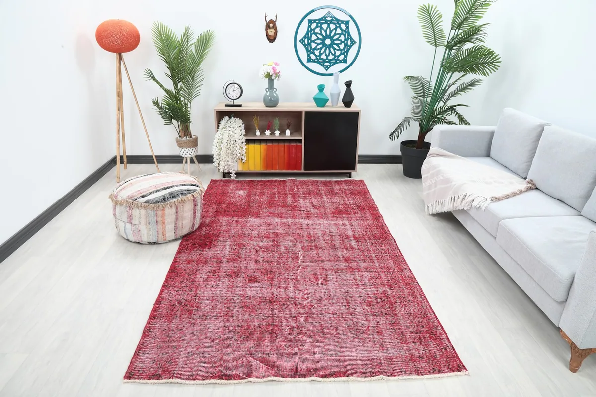 Vintage rose rug in a modern living room setting with a sofa and pouf.