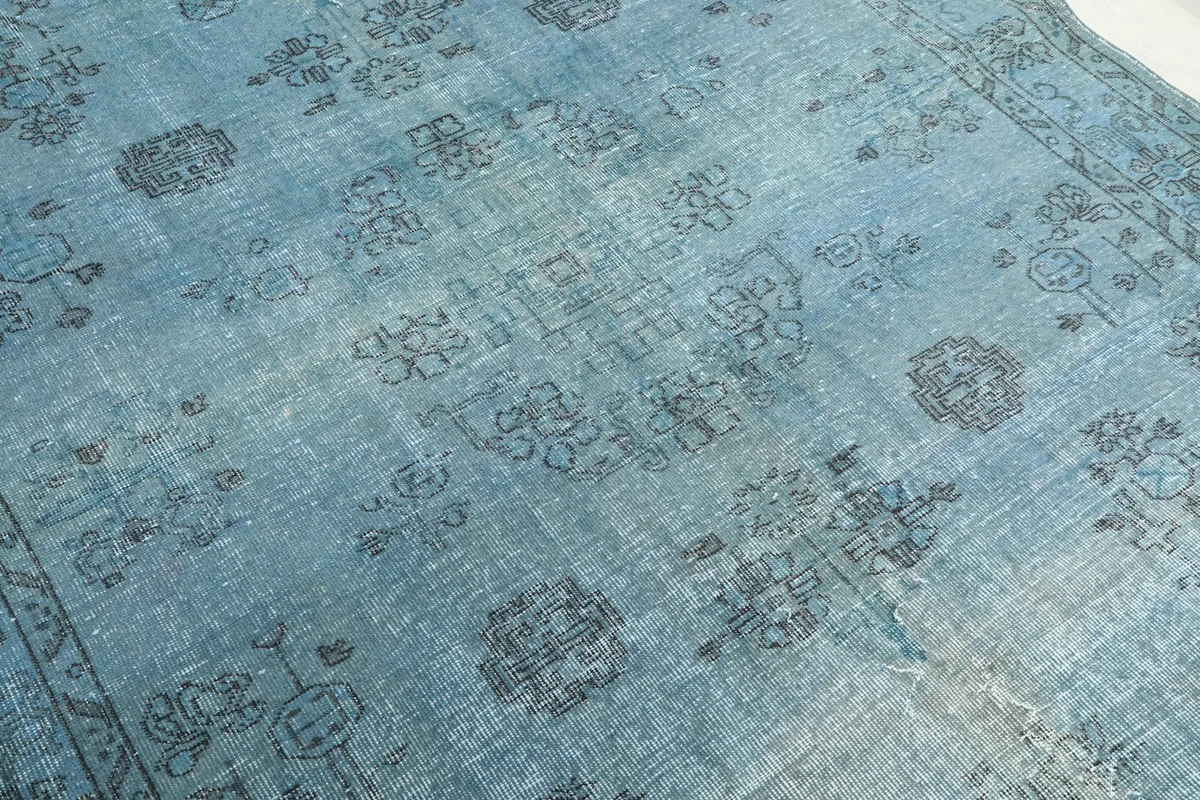 Close-up of the rug's field, highlighting the faded blue color and detailed charcoal patterns