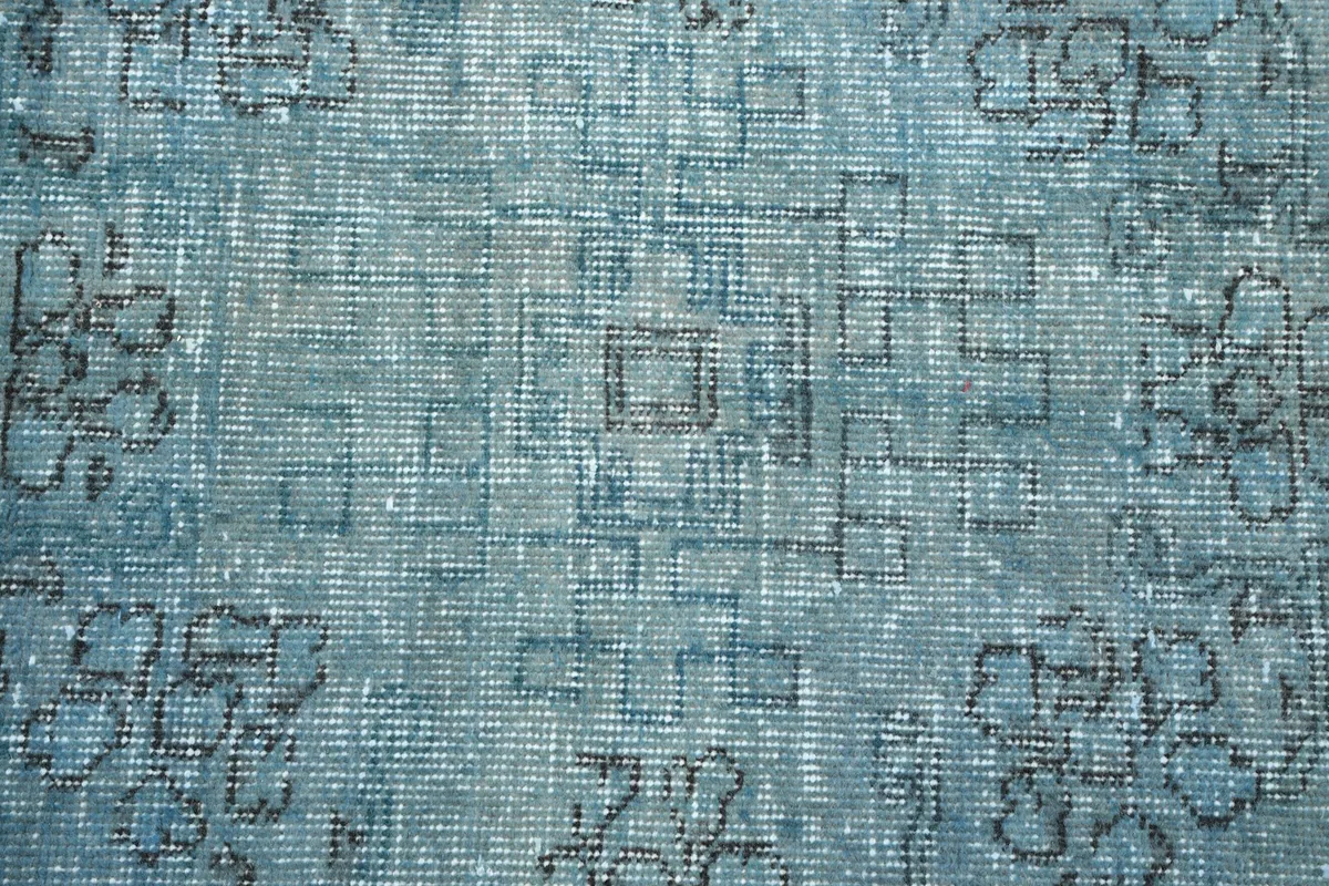 Texture and wear visible in the blue wool pile, showing subtle geometric variations