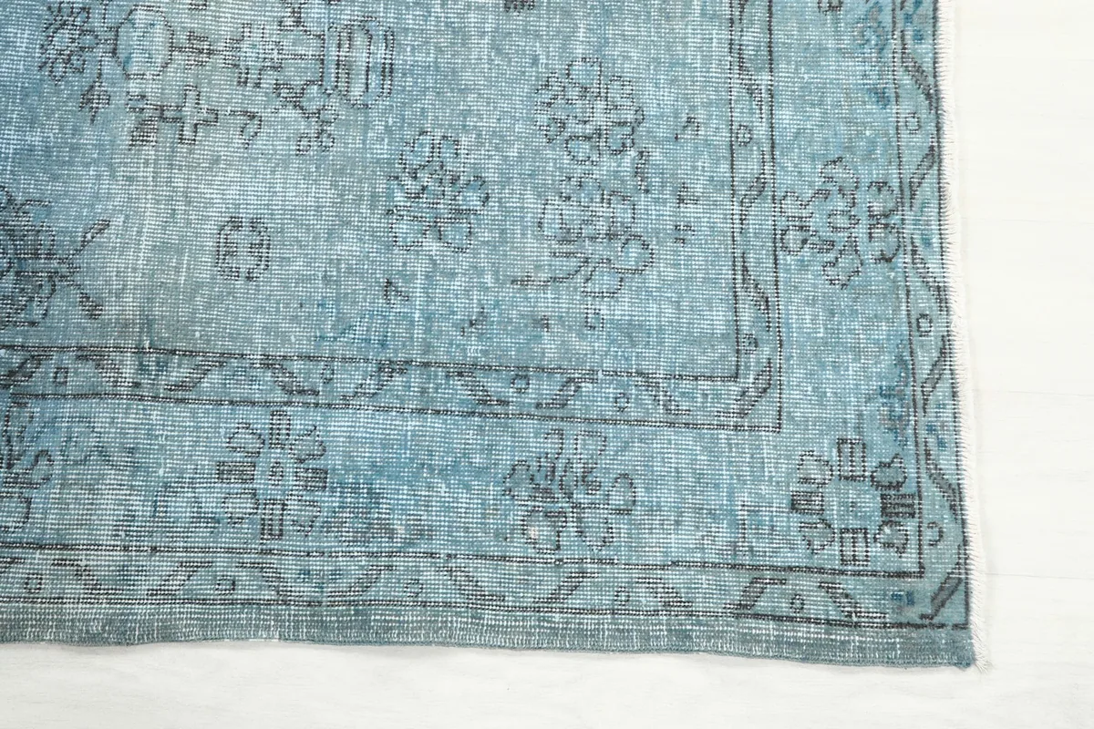 Detailed view of the corner border design with intricate charcoal geometric motifs on a blue field