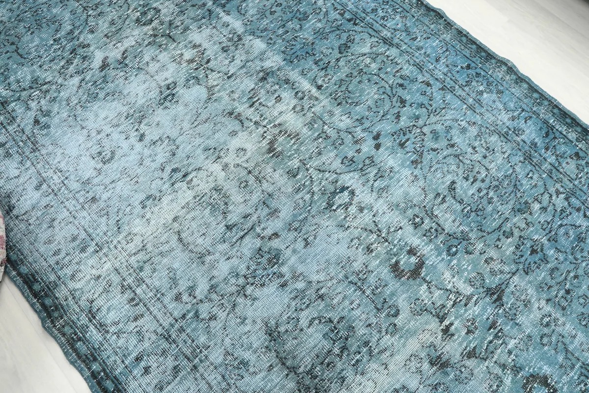 Close-up view of the rug's surface, highlighting the worn pile and subtle pattern variations.